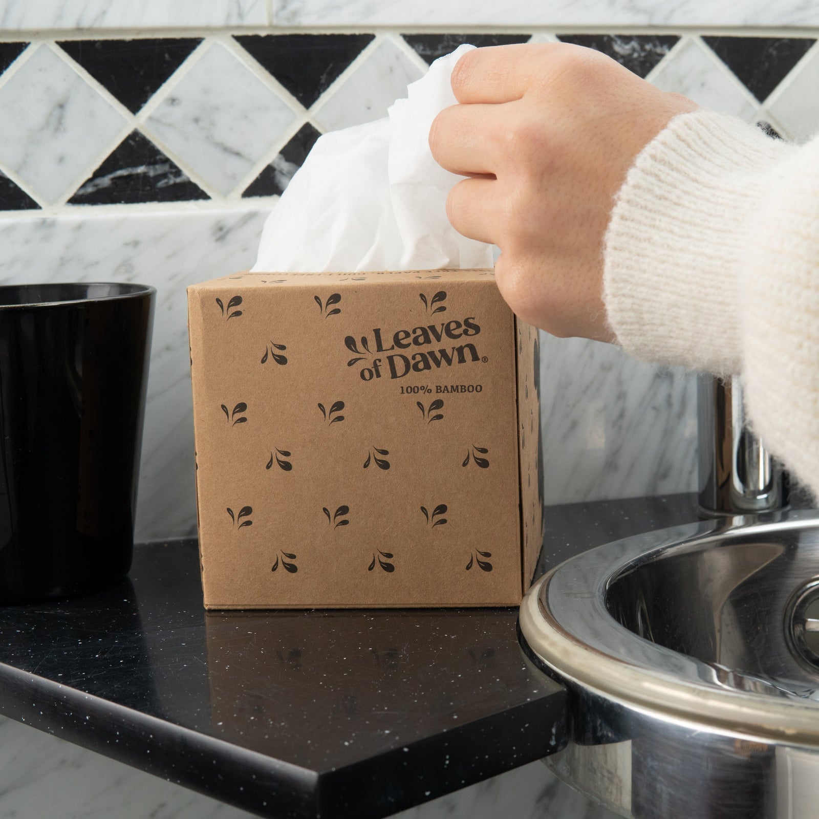 Leaves of Dawn bamboo tissue paper open box, hand taking one tissue.